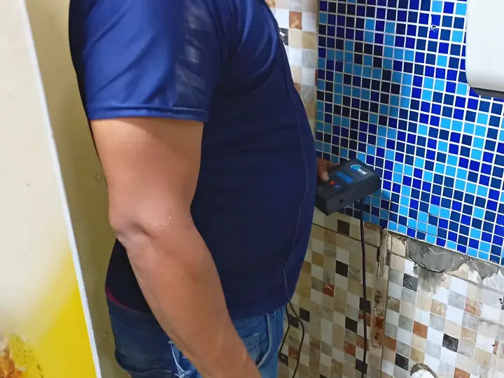 Técnico com geofone na parede de um banheiro