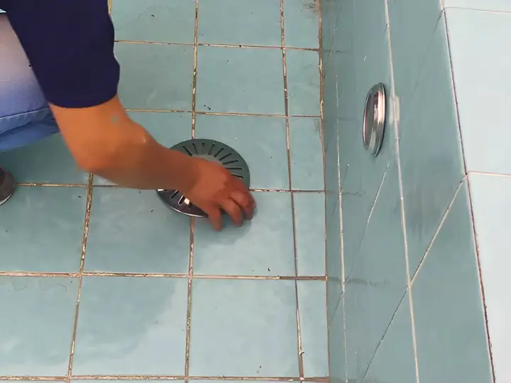 Técnico inspecionando o ralo de fundo de uma piscina vazia