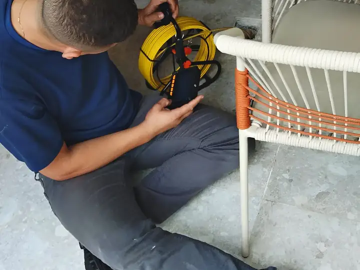 Técnico preparando a câmera de inspeção sentado no piso de um salão