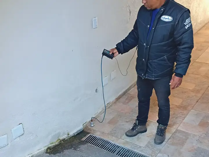 Técnico com geofone varrendo o piso de uma área externa